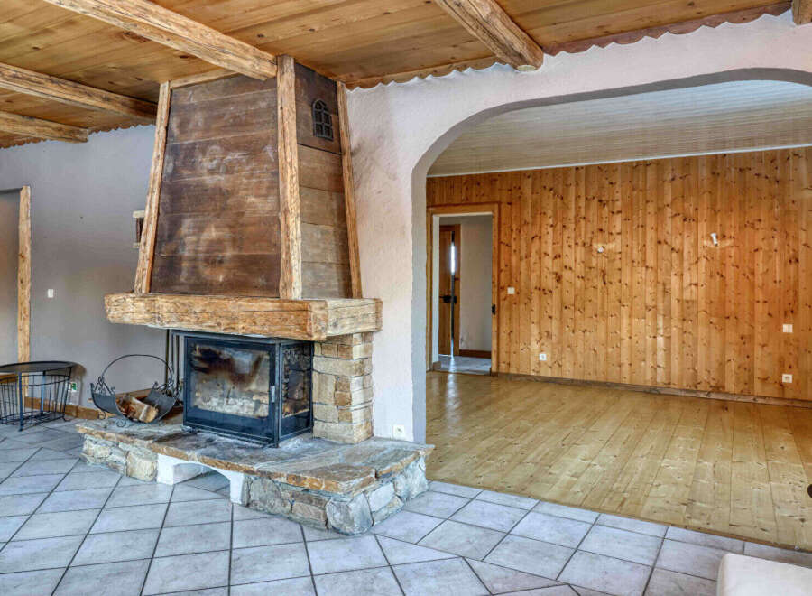 This stunning property boasts a rustic charm with its wooden ceiling and a striking fireplace, creating a warm and inviting atmosphere.