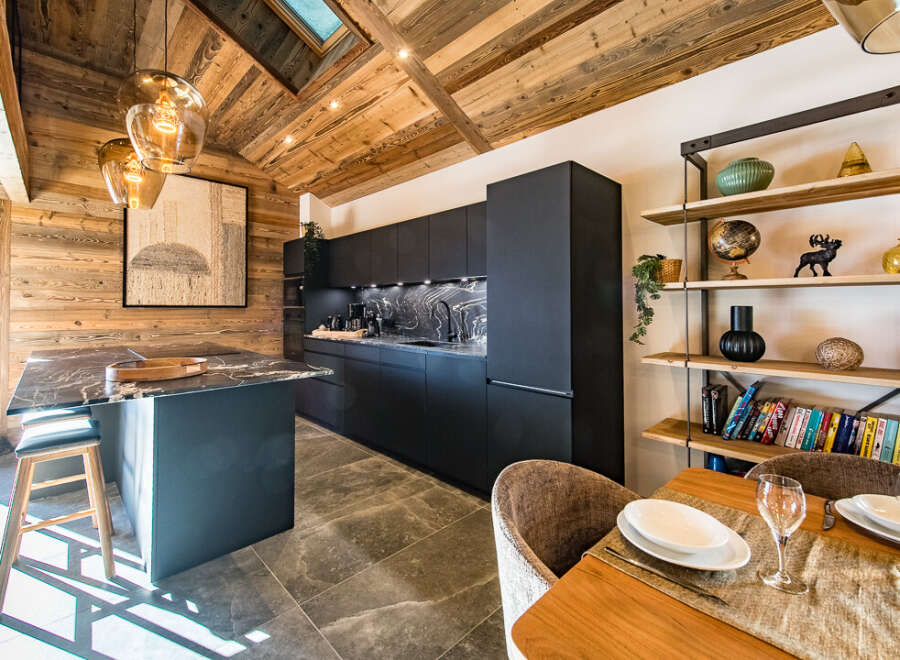 Experience luxury living in this stunning property featuring a modern kitchen with sleek black cabinetry and a marble countertop.