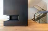 This modern home boasts a sleek, minimalist design with a stunning black fireplace as its focal point.
