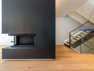 This modern home boasts a sleek, minimalist design with a stunning black fireplace as its focal point.