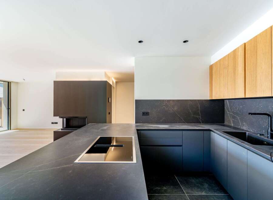This modern kitchen boasts sleek, dark countertops and cabinetry, creating a sophisticated and stylish space.