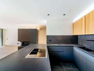 This modern kitchen boasts sleek, dark countertops and cabinetry, creating a sophisticated and stylish space.