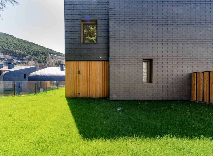 This modern architectural marvel showcases a stunning facade with a combination of dark slate and warm wooden accents.