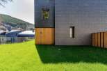 This modern architectural marvel showcases a stunning facade with a combination of dark slate and warm wooden accents.