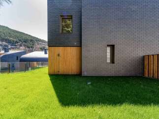 This modern architectural marvel showcases a stunning facade with a combination of dark slate and warm wooden accents.