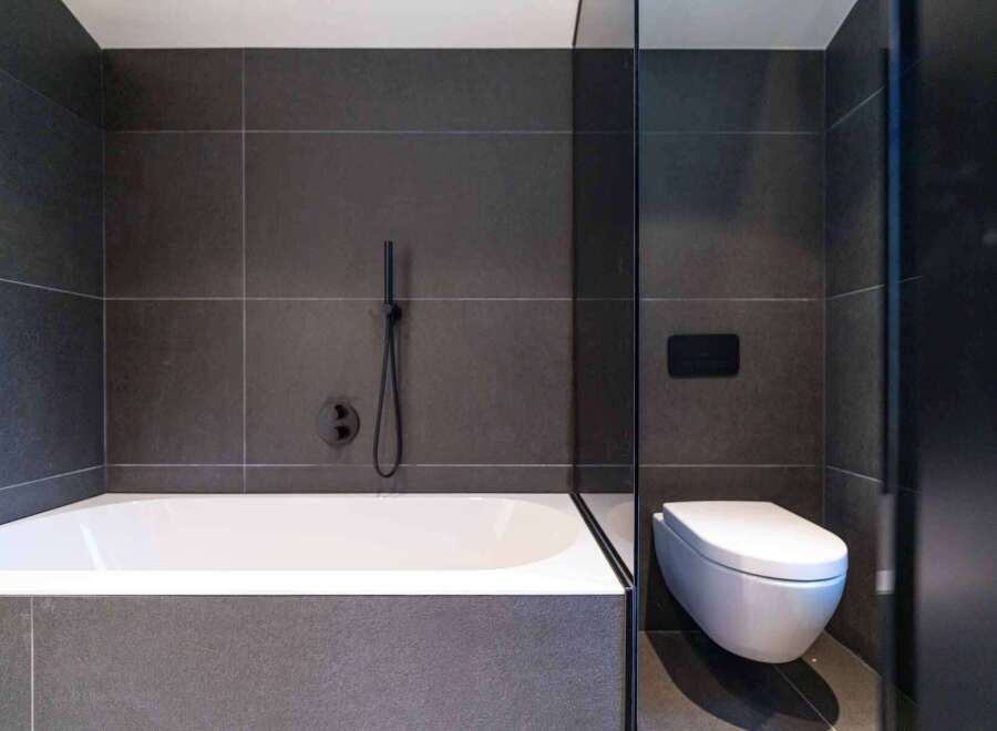 This modern bathroom features a sleek design with dark gray tiles and a minimalist aesthetic.