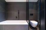 This modern bathroom features a sleek design with dark gray tiles and a minimalist aesthetic.