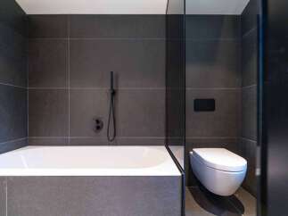 This modern bathroom features a sleek design with dark gray tiles and a minimalist aesthetic.