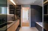 This modern bathroom showcases a sleek design with dark gray tiles and a wooden vanity.