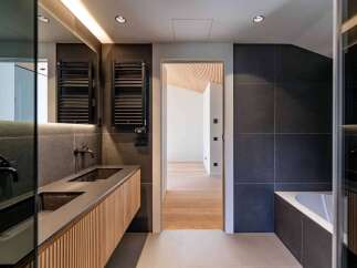 This modern bathroom showcases a sleek design with dark gray tiles and a wooden vanity.