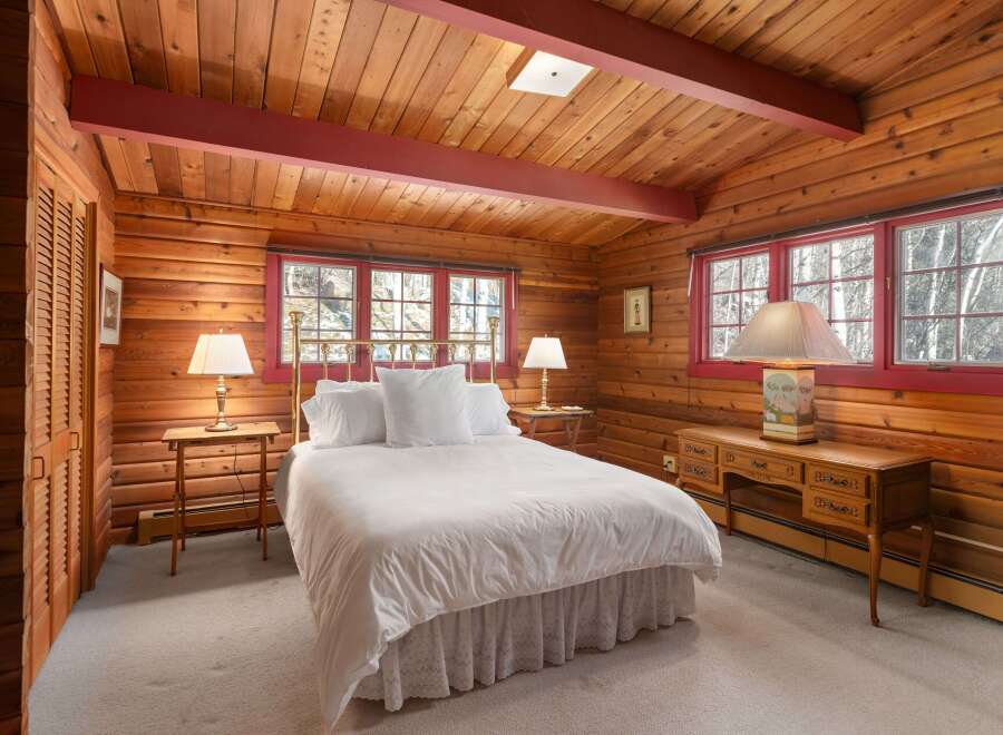 Step into a cozy bedroom retreat featuring rustic wood paneling and a charming ambiance.