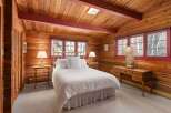 Step into a cozy bedroom retreat featuring rustic wood paneling and a charming ambiance.