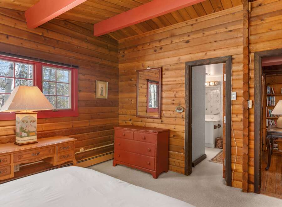 Step into rustic charm with this inviting bedroom, featuring warm wood paneling and a cozy ambiance.