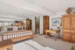 This spacious bedroom offers a serene retreat with its light-filled ambiance and elegant design.