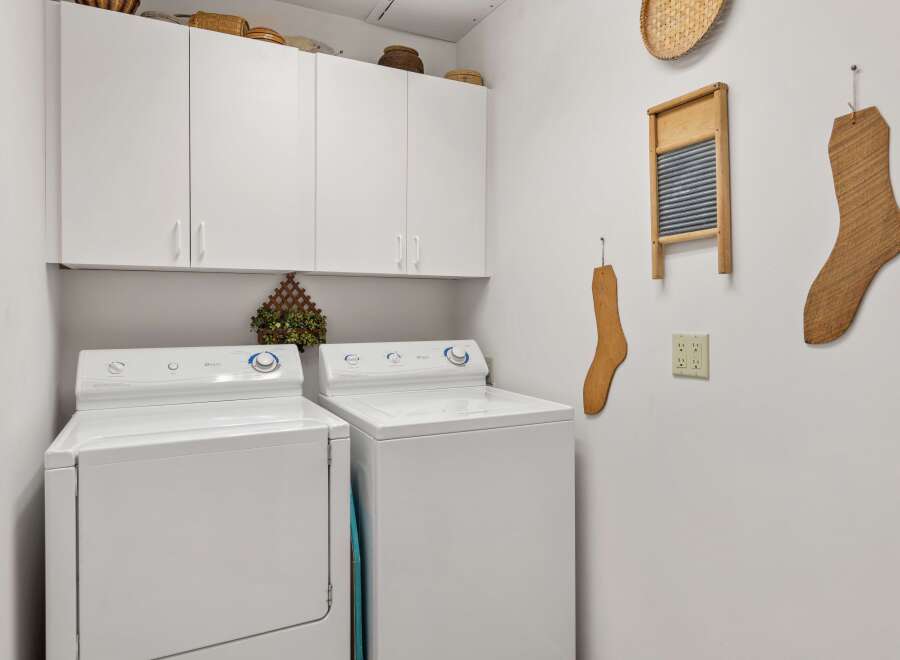 This laundry room features a modern design with white appliances and ample storage.
