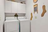 This laundry room features a modern design with white appliances and ample storage.