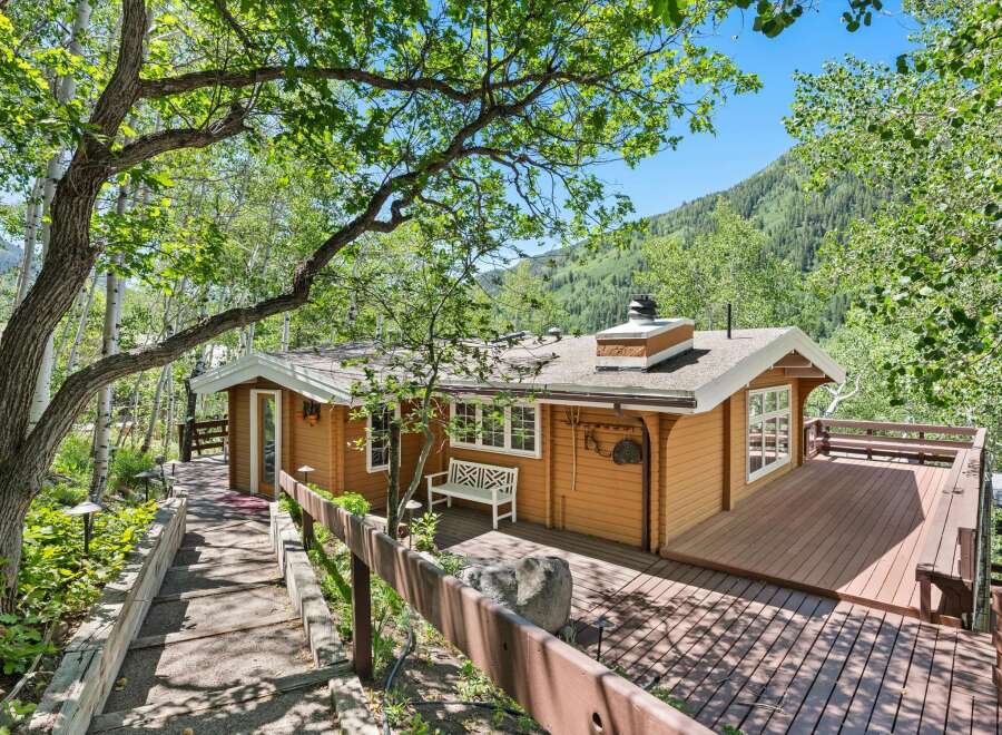 Nestled amidst lush greenery and mature trees, this charming cabin offers a serene mountain retreat.