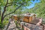 Nestled amidst lush greenery and mature trees, this charming cabin offers a serene mountain retreat.