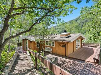 Nestled amidst lush greenery and mature trees, this charming cabin offers a serene mountain retreat.
