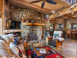 Step into rustic luxury with this stunning property featuring a grand stone fireplace, perfect for cozy evenings.