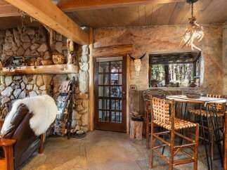 Step into rustic elegance with this stunning property, featuring a cozy stone fireplace and exposed wooden beams.