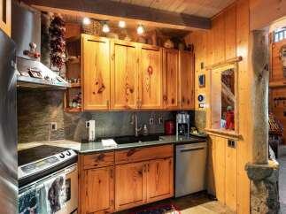 This charming kitchen boasts rustic wooden cabinetry and a sleek, modern countertop, creating a perfect blend of style and functionality.