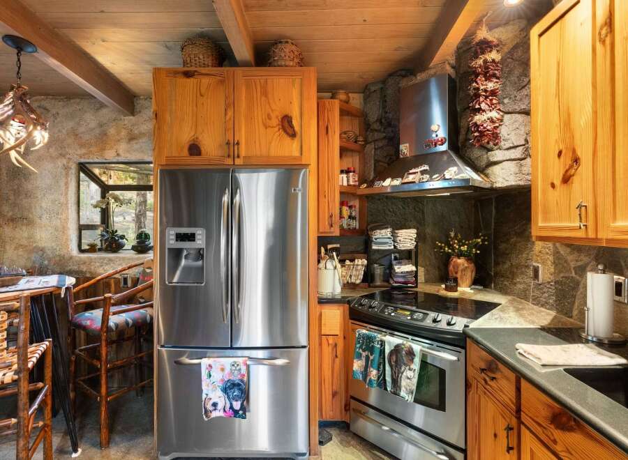 Step into this rustic kitchen, featuring a stainless steel refrigerator and a modern cooktop.