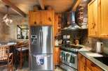 Step into this rustic kitchen, featuring a stainless steel refrigerator and a modern cooktop.