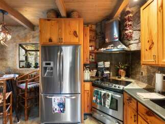 Step into this rustic kitchen, featuring a stainless steel refrigerator and a modern cooktop.