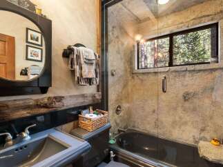This rustic bathroom features a unique stone-like wall design and a dark-colored bathtub, creating a cozy and inviting atmosphere.