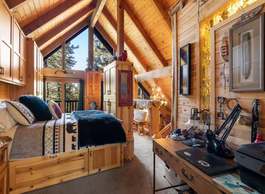 Discover the charm of this cozy cabin retreat, featuring a rustic bedroom with a comfortable bed and a stunning view.