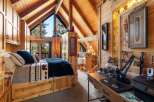 Discover the charm of this cozy cabin retreat, featuring a rustic bedroom with a comfortable bed and a stunning view.