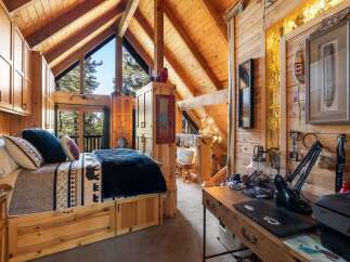 Discover the charm of this cozy cabin retreat, featuring a rustic bedroom with a comfortable bed and a stunning view.