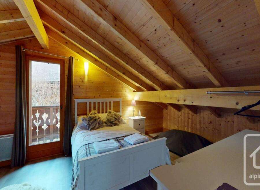 Discover the charm of this cozy bedroom, featuring a rustic wooden interior and a comfortable bed.