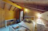 This charming bedroom features a cozy, rustic design with wooden walls and a sloped ceiling, creating a warm and inviting atmosphere.
