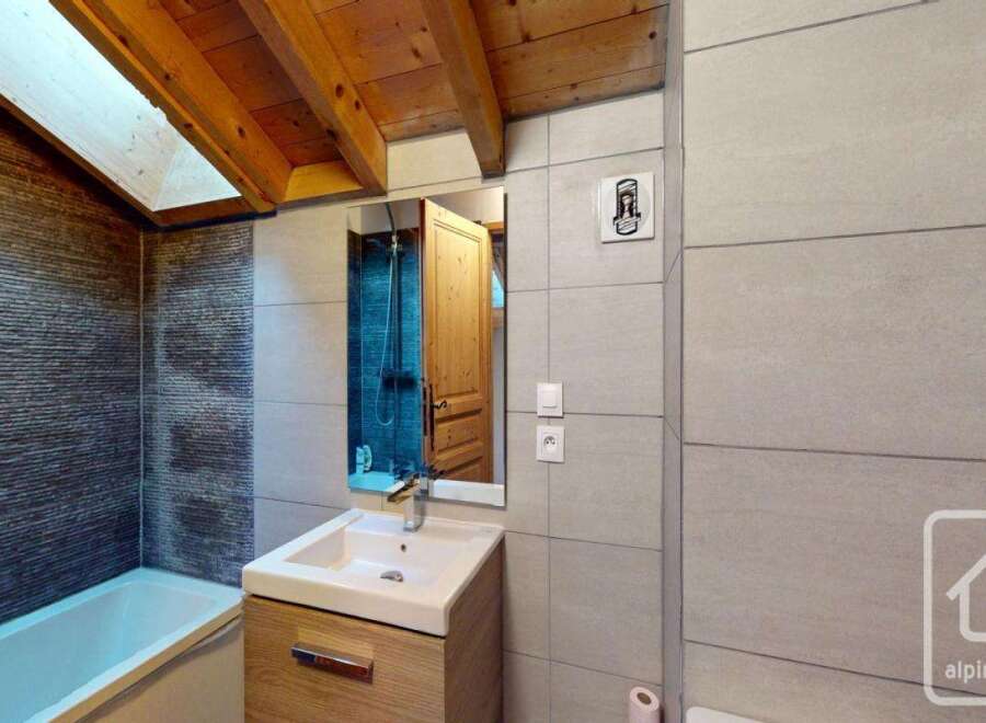 This stunning bathroom features a modern design with a wooden vanity and a sleek sink.