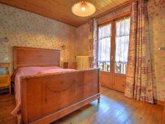 This charming bedroom features a classic wooden bed frame, complemented by floral wallpaper and wooden flooring.
