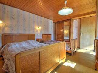 This charming bedroom features a warm, inviting atmosphere with its wooden ceiling and matching furniture.