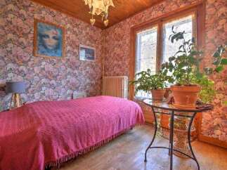 Charming bedroom with floral wallpaper and a cozy bed.