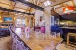 Experience luxury living in this stunning property, featuring a spacious dining area with a rustic wooden table and modern clear chairs.