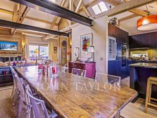 Experience luxury living in this stunning property, featuring a spacious dining area with a rustic wooden table and modern clear chairs.