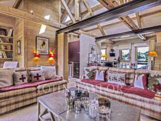 Experience luxury living in this stunning property, featuring a cozy living room with a fireplace and exposed wooden beams.