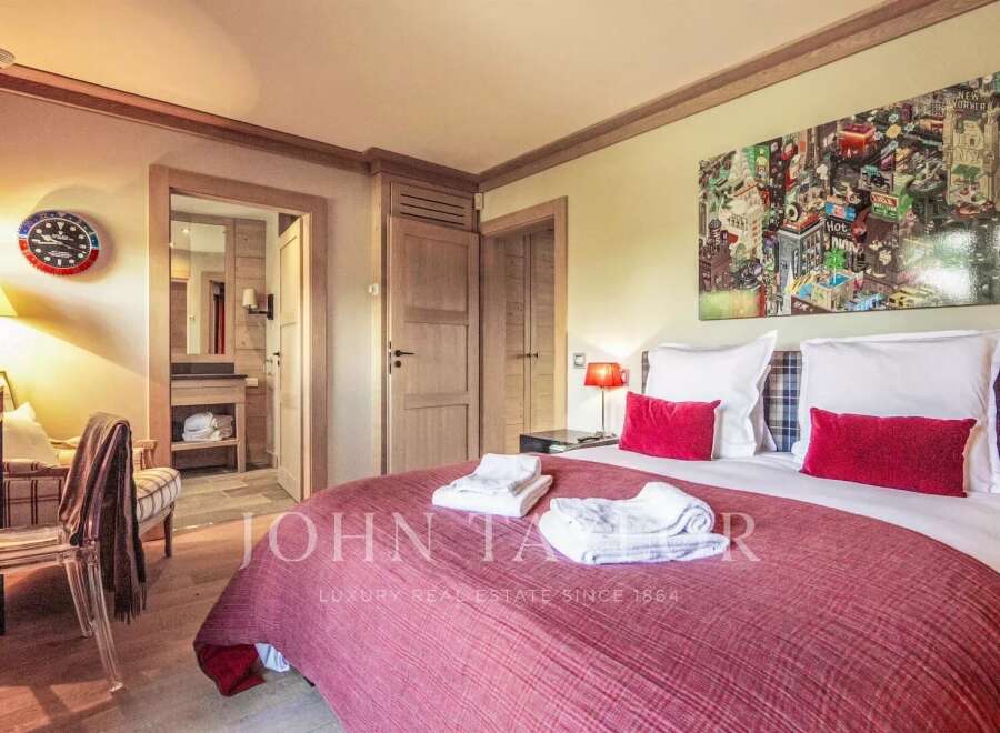 Experience luxury living in this exquisite bedroom, featuring a cozy bed adorned with plush pillows and a vibrant red comforter.