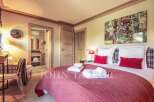 Experience luxury living in this exquisite bedroom, featuring a cozy bed adorned with plush pillows and a vibrant red comforter.