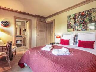 Experience luxury living in this exquisite bedroom, featuring a cozy bed adorned with plush pillows and a vibrant red comforter.