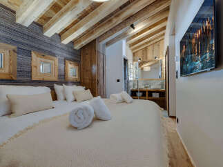 Experience luxury in this stunning bedroom featuring a cozy bed, plush pillows, and rolled towels.