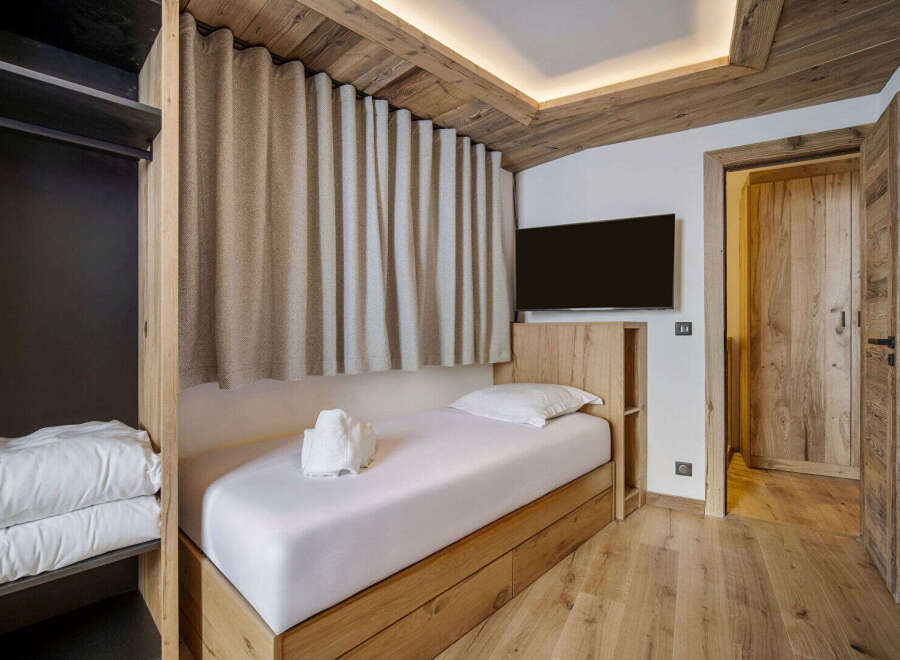 Discover the charm of this cozy bedroom, featuring a comfortable single bed and elegant wooden accents.