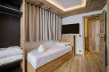 Discover the charm of this cozy bedroom, featuring a comfortable single bed and elegant wooden accents.