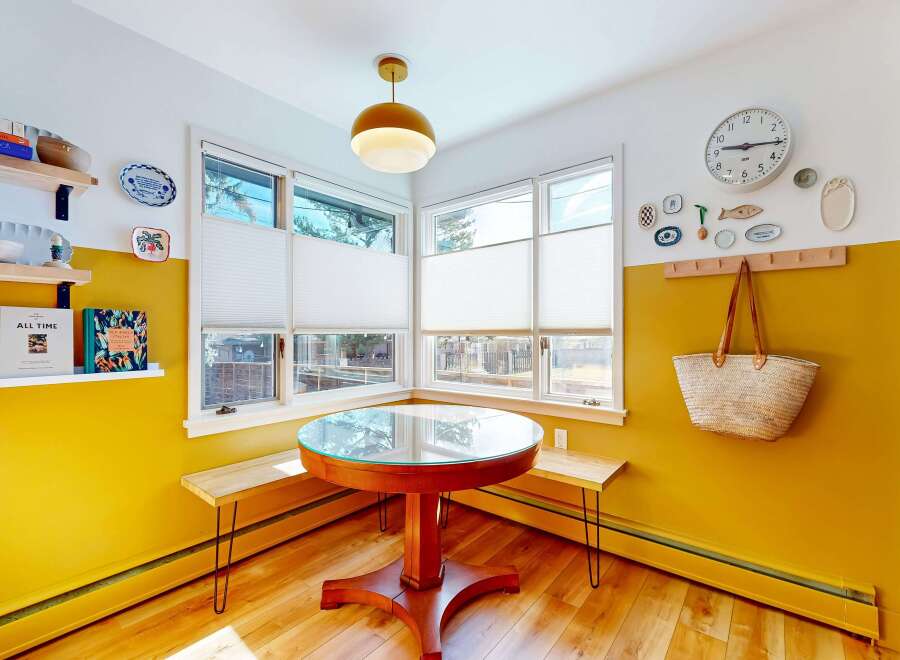 This charming dining nook features a round table with a glass top, surrounded by built-in benches, creating an inviting space for meals.