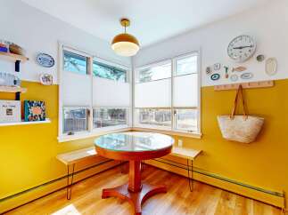 This charming dining nook features a round table with a glass top, surrounded by built-in benches, creating an inviting space for meals.